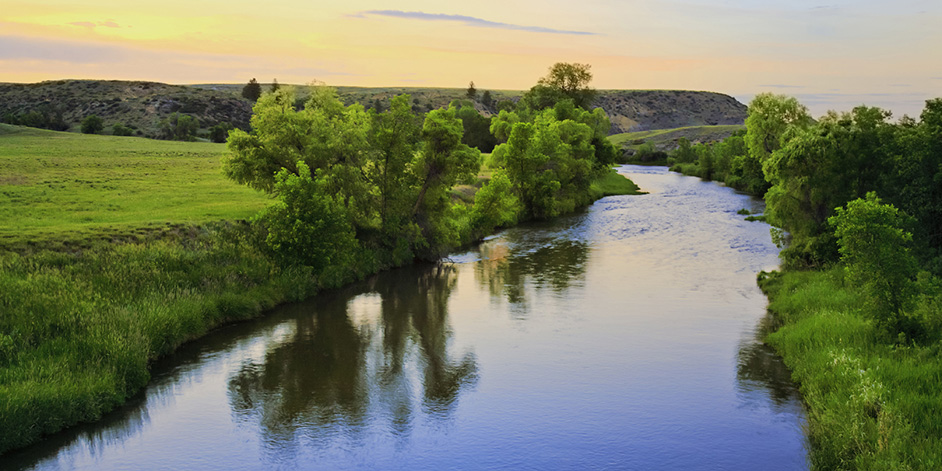 A stream winds through the Montana landscape at sunset